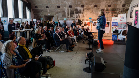 Humorvolle Moderation durch Tanja Föhr Voller Veranstaltungsraum, Teilnehmende sichtlich amüsiert über die Anmoderation von Moderatorin Tanja Föhr (rechts im Bild)