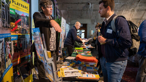 Austauschbörse verschiedener Aussteller mit Angeboten für Bewegungsförderung im öffentlichen Raum Seitenansicht der gut besuchten Austauschbörse verschiedener Aussteller mit Angeboten für Bewegungsförderung im öffentlichen Raum.
