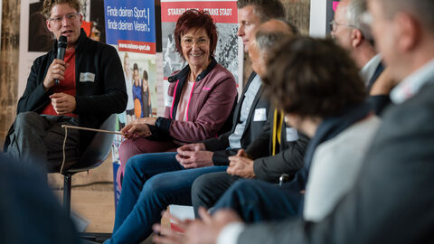 Intersektoral besetzte Diskussionsrunde rund um Anliegen der Bevölkerung und der Teilnehmenden Intersektoral besetzte Diskussionsrunde rund um Anliegen der Bevölkerung und der Teilnehmenden. Hier ist eine lächelnde Barbara Schader zu sehen, die Richtung Moderatorin schaut. Rechts und links von ihr sitzen weitere Podiumsgäste.