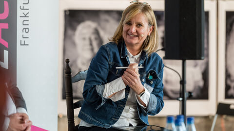 Moderatorin Tanja Föhr Seitenansicht von der Moderatorin Tanja Föhr die lächeln zu den Podiumsgästen schaut