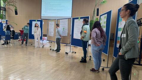 Teilnehmende stellen einzelne Good Practice-Kriterien anhand der Patenschaft-Methode vor: die Zusammenfassung der Kriterien ist auf Flipchart Papieren an Pinnwänden befestigt.