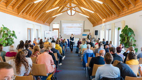 Hauptraum (Raum Sonne) der Fachtagung in Fulda Hauptraum der Fachtagung zu Beginn der Veranstaltung. Der Saal ist mit Menschen gefüllt, die ihre Aufmerksamkeit nach vorne zur Moderatorin richten.