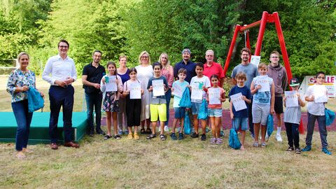 Auf der Liegewiese des Hallendbads in Rodheim-Biebertal gab es für die gerade ausgezeichneten „Seepferdchen“ und „Freischwimmer“ von Schul- und Sportdezernent Christopher Lipp (2. v. l.) als Erinnerung an das Sommer-Schwimm-Camp 2022 neben Teilnahmeurkunden auch Sportbeutel mit Handtüchern. 