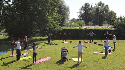 Menschen stehen im Kreis. Sie machen gemeinsam im Park Bewegungsübungen.