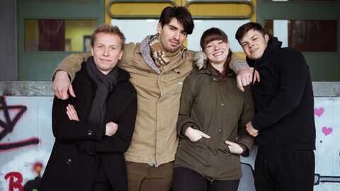 Vier Personen in einer Reihe, die sich freundschaftlich im Arm halten.