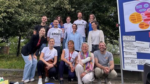 Gruppenbild 2. Austauschtreffen BWK 2024 Mehrere Personen stehen und hocken in einer Gruppe vor Bäumen