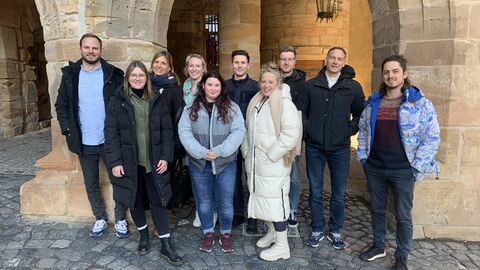 Gruppenbild beim Austauschtreffen der Bewegungskoordinierenden Gruppenbild mir mehreren Personen vor einem historischen Torbogen