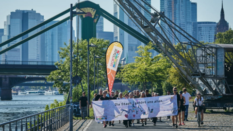 Gruppe von Menschen läuft mit buntem Banner ein Weg