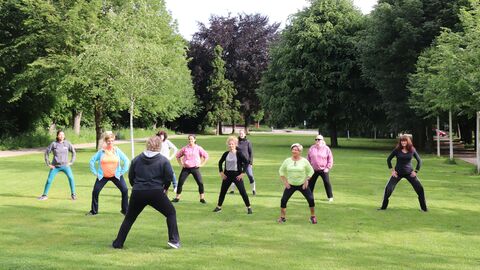 Menschen machen angeleiteten Sport auf einer Wiese im Park