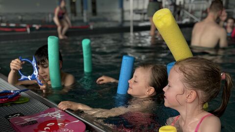 Kinder mit Pool-Nudeln im Schwimmbadbecken