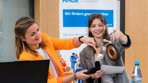 Eröffnung der Veranstaltung durch die Moderatorinnen (Béatrice Frank und Lena Ondrasch, HAGE) Frauen schlagen gemeinsam Gong an Rednerpult