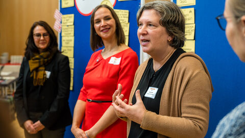Vorstellung der Lebensweltexpertinnen in der Lebenswelt Betrieb, v.l.n.r.: Petra Kraus (HMFG), Jana Douchin (AOK Hessen, BGF-Koordinierungsstelle), Christine Breser (ivm Gmbh, Integriertes Verkehrs- und Mobilitätsmanagement) Drei Frauen vor der Pinnwand sprechen mit Gruppe