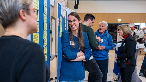 Lebensweltexpertin Lisa Birkenhauer (AWO Kita Bockenheim) und Lebensweltmoderation (Niklas Poellath) im Austausch mit Teilnehmenden (Lebenswelt: Kindertagesbetreuungsstätten) Mehrere Personen unterhalten sich in verschiedenen Kleingruppen