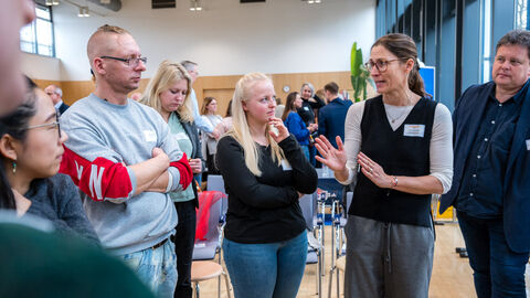 Lebensweltexpertin Karen Zacharides (Bildungsakademie des lsb h) und Lebensweltexperte Markus Schindler (AOK Hessen, Pflegekassen) im Austausch mit Teilnehmenden (Lebenswelt Senioren- und Pflegeeinrichtungen) Mehrere Personen unterhalten sich angeregt