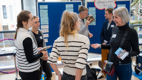 Lebensweltexpertin Linda Obermeyer (ISA - Internationales Stadtbauatelier) im Austausch mit Teilnehmenden (Lebenswelt: Öffentlicher Raum) Mehrere Personen unterhalte sich in einer Kleingruppe