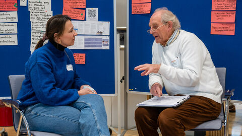 Speaker's Corner: Lebensweltexperte Dr. Harald Seehausen beim Austausch mit einer Teilnehmerin (Lebenswelt: (Sport)Verein) Zwei Personen sitzen vor einer Pinwand auf Stühlen und unterhalten sich angeregt.