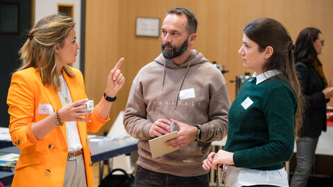 Moderatorin Béatrice Frank (HAGE) im Austausch mit Teilnehmenden Drei Personen unterhalten sich angeregt