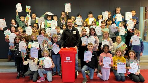 Gruppenbild Grundschüler mit Urkunden in der Hand und roter Tonne mit Material