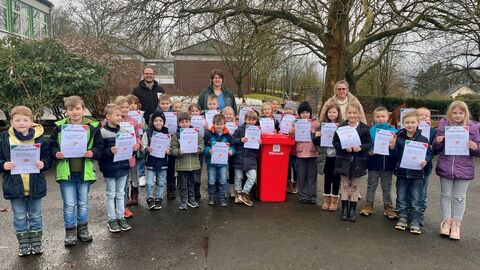 Gruppenbild Grundschulkinder und Erwachse im Freien mit Urkunden und roter Bewegungstonne