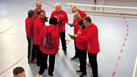 Viele Personen n roten Jacken (Testhelfer und Testhelferinnen) bespreche sich im Kreis