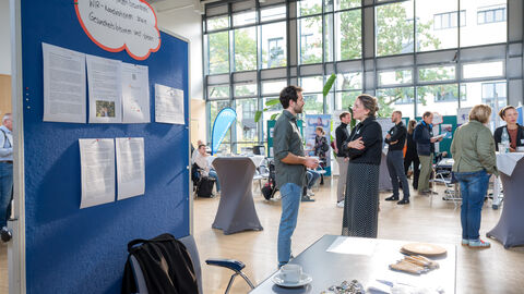 Teilnehmende tauschen sich zwischen den Ständen auf dem Markt der Möglichkeiten aus.