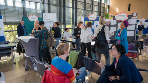 Teilnehmende tauschen sich zwischen den Ständen auf dem Markt der Möglichkeiten aus.