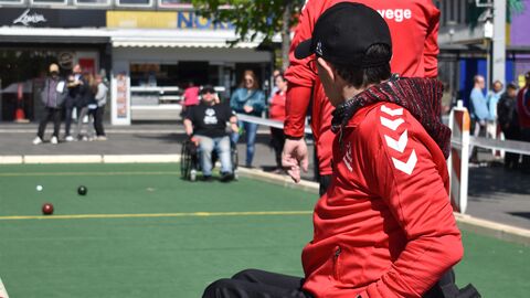 Mann mit Kappe im Rollstuhl spielt Boccia