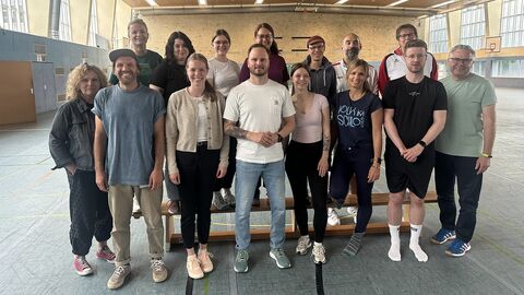 Gruppenbild von Erwachsenen in Sportbekleidung in einer Turnhalle